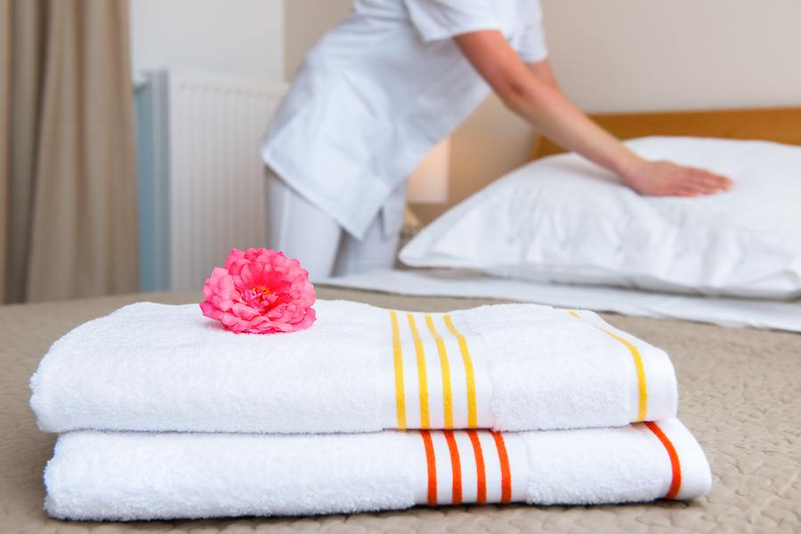 Maid making bed in hotel room